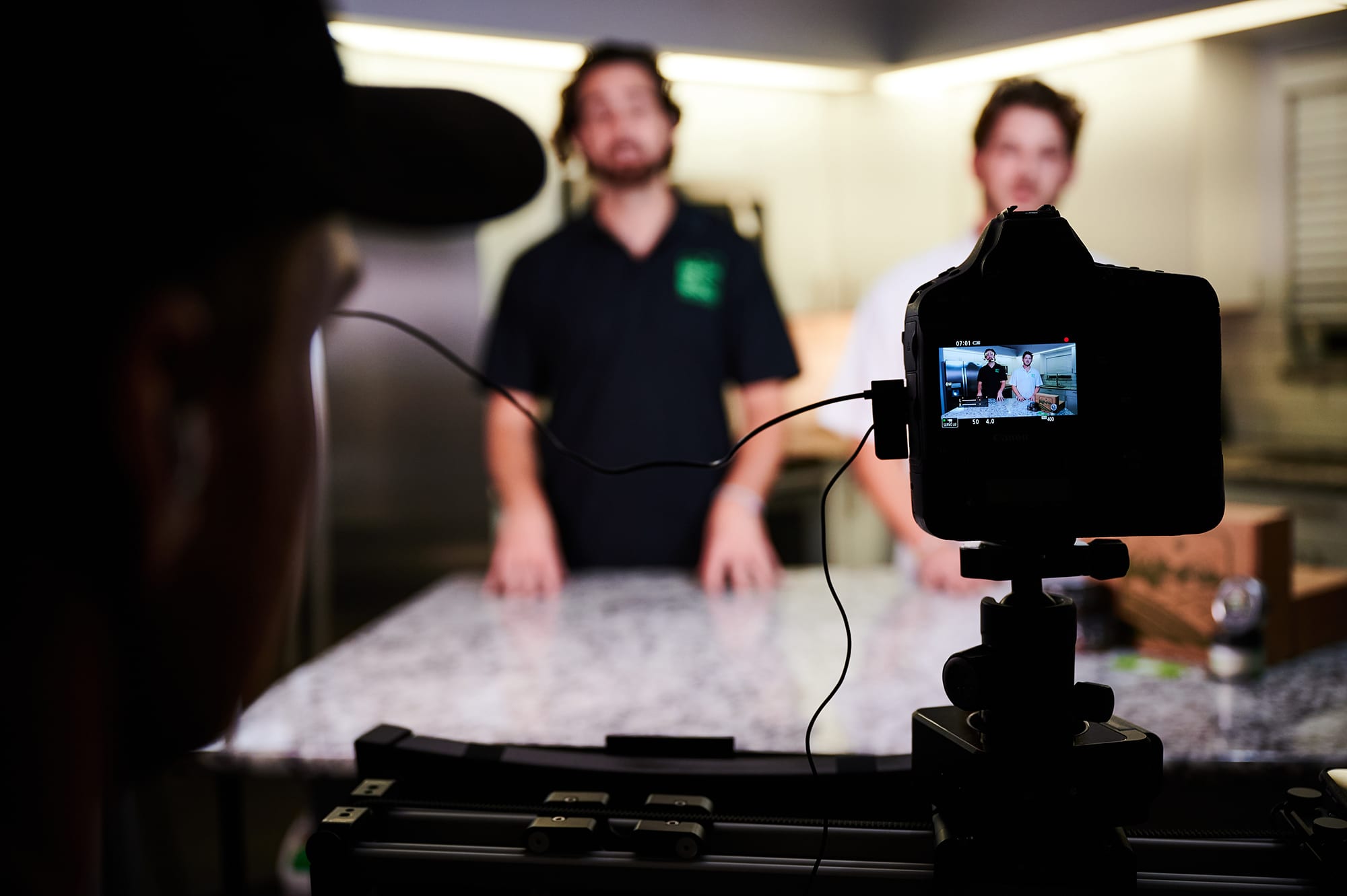 Adam Rahman and a Fresh Bros colleague filming product education material behind a kitchen counter