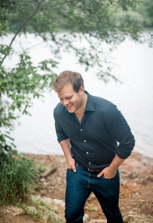 Adam Ryan smiling while walking beside trees and water