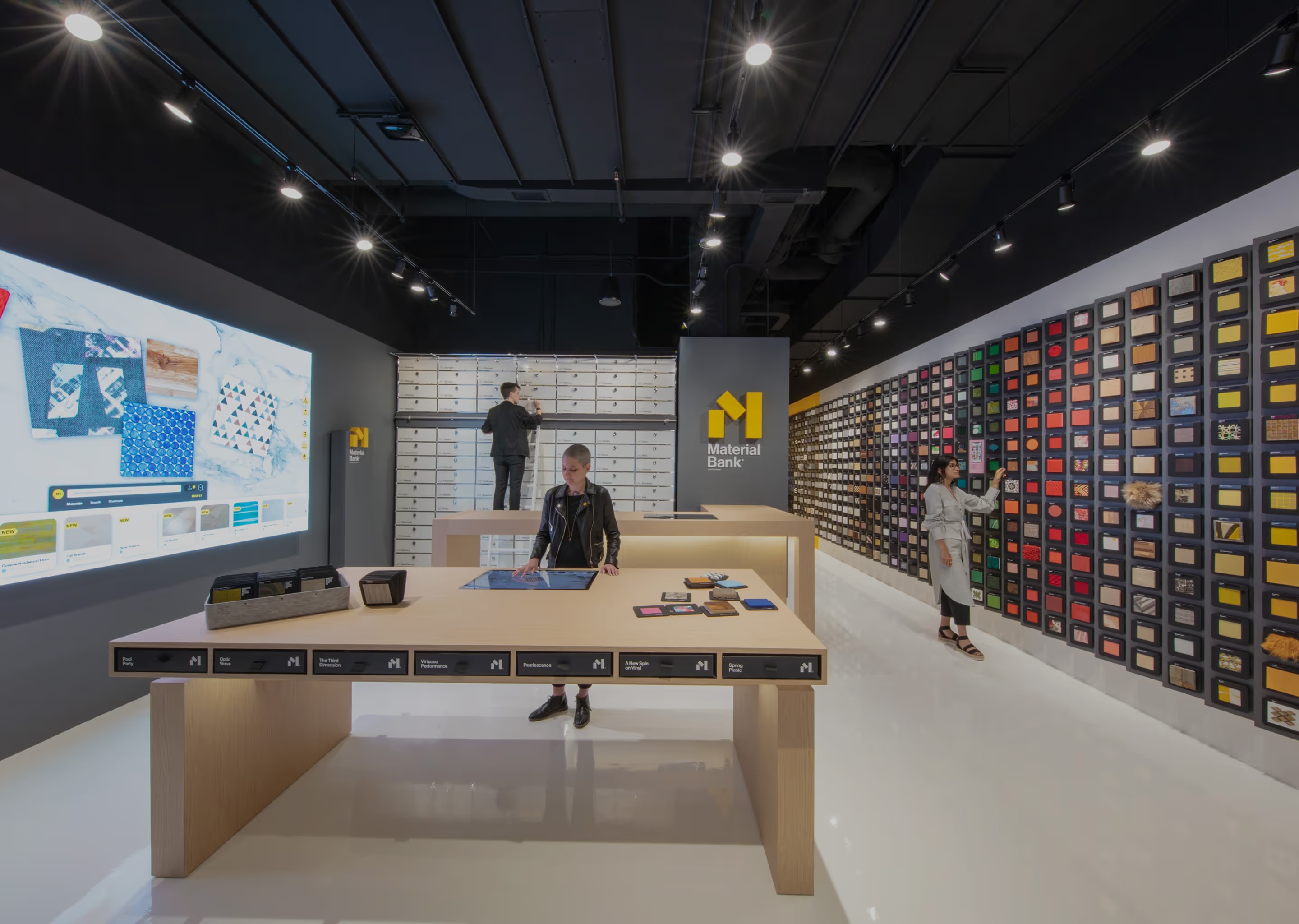 Visitors exploring material displays and an interactive table inside a Material Bank space