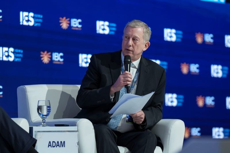 Adam Schwarz holding a microphone and papers while moderating at the Indonesia Economic Summit 2026