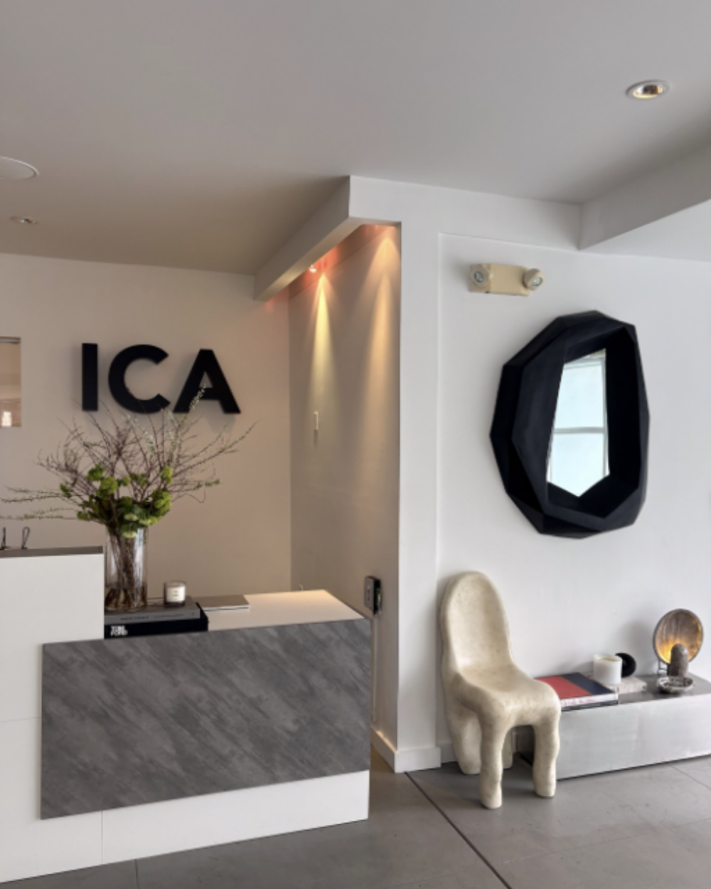 The ICA Sunset reception area, with a stone-front desk, flowers and sculptural chair