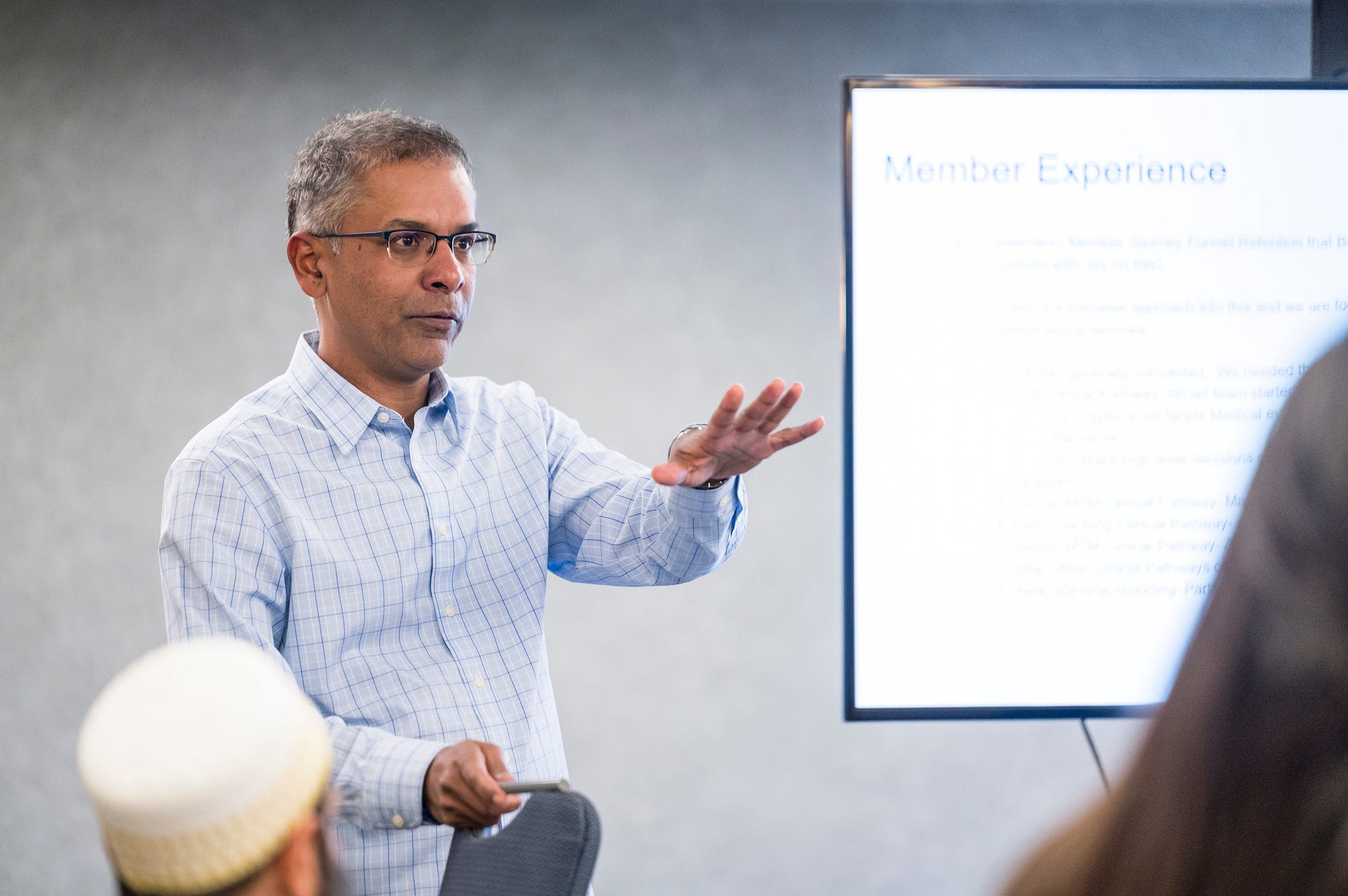 Adnan Asar presenting to a group beside a screen