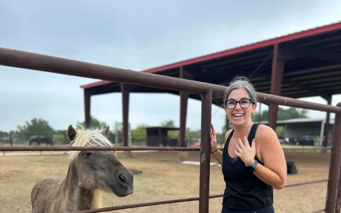 Adrianna Nowell laughing beside a small horse at Restoration Ranch in Texas