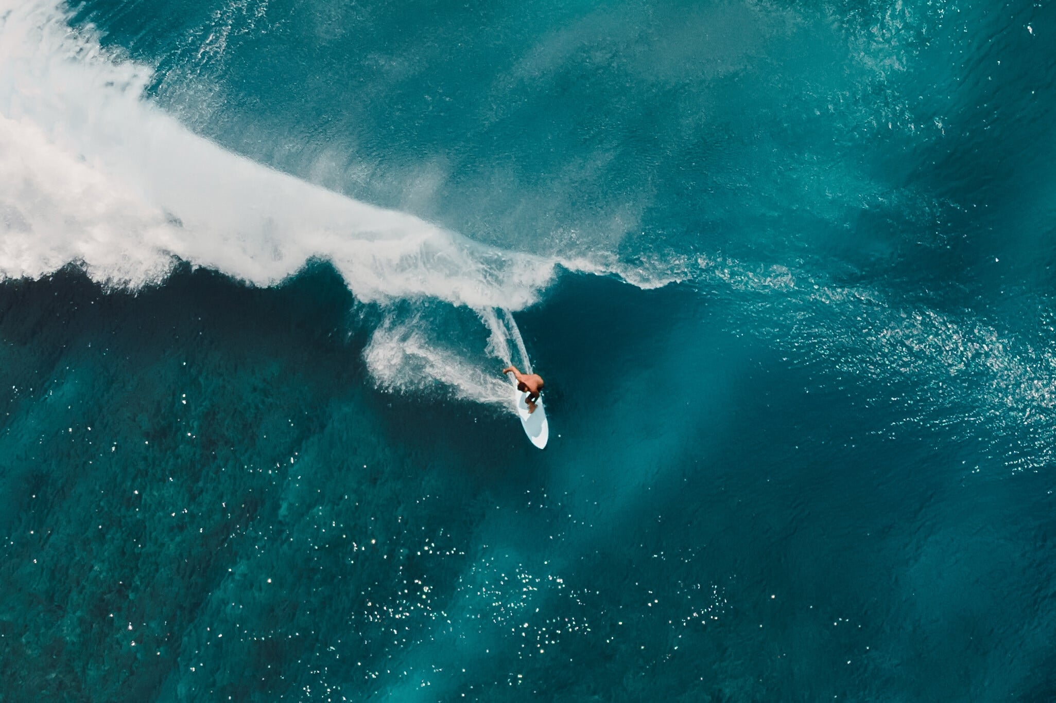 A surfer riding a breaking turquoise wave