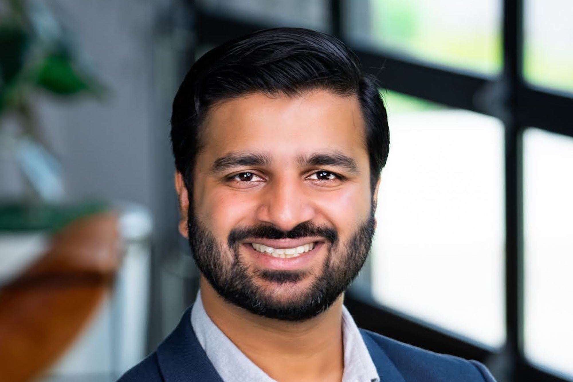 Advait Shinde smiling beside a window in a GoGuardian press photograph