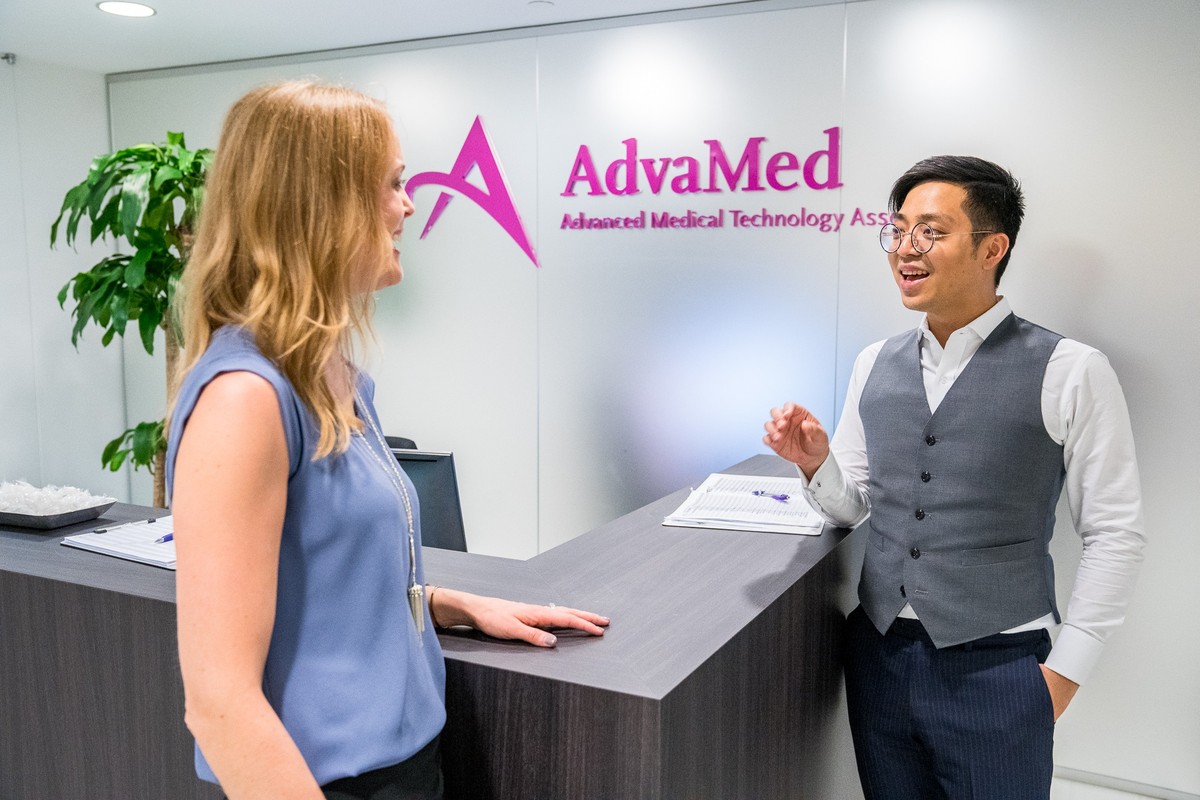 Two people talking at a reception desk in an AdvaMed workplace