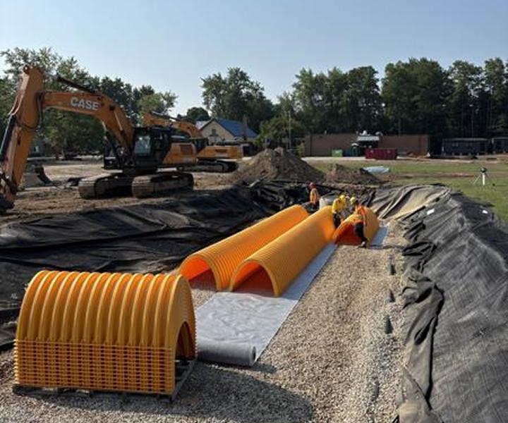 Yellow StormTech SC-800 chambers being installed in a stone-lined excavation