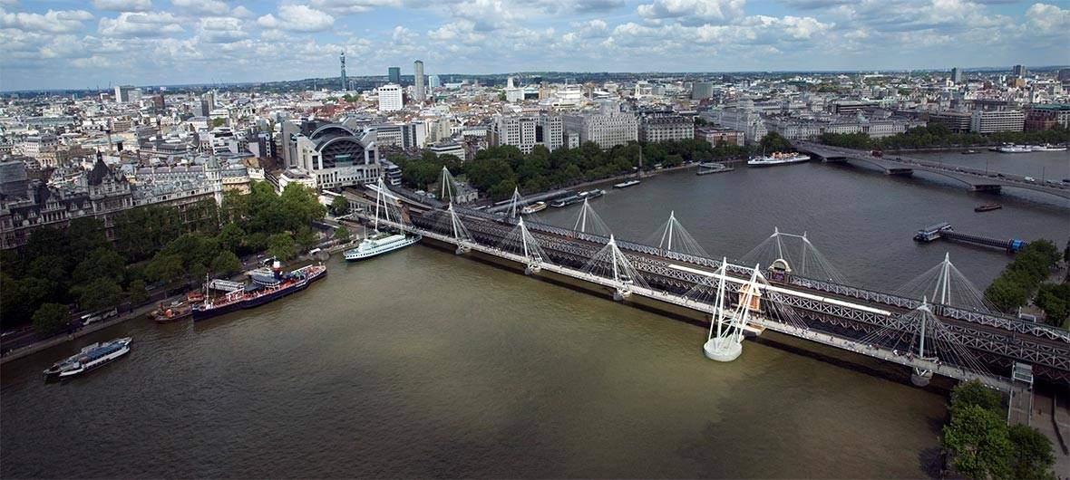 The Thames and central London seen from above, with railway and pedestrian bridges in the foreground