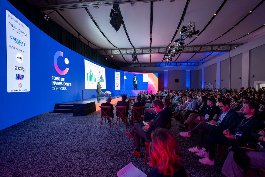 An audience faces speakers and blue presentation screens at the 2026 Foro de Inversiones Córdoba.