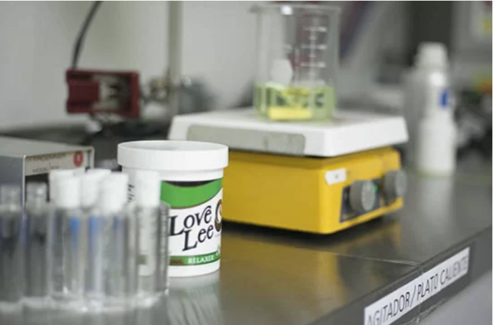 A Love Lee relaxer container beside glassware and laboratory equipment at Envasadora Comercial.