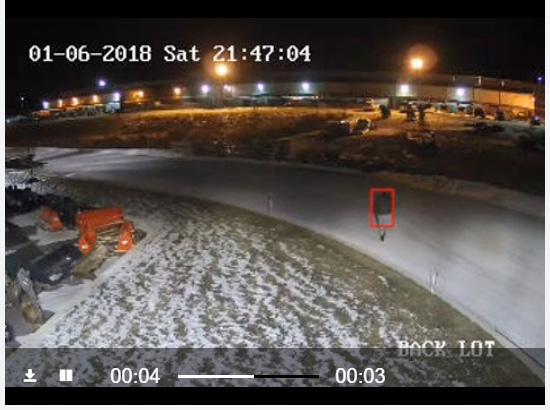 Nighttime surveillance view of a Dallas tractor dealership with a red detection rectangle around an intruder