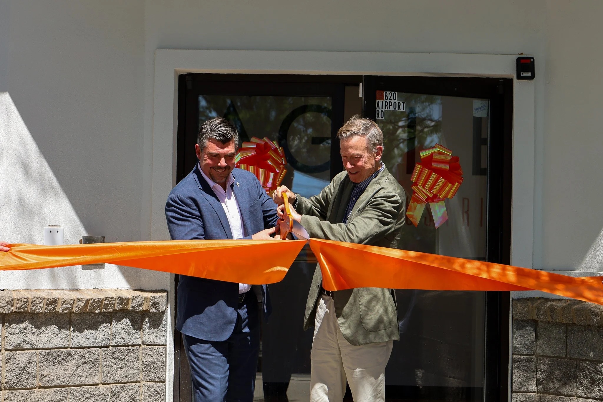 Chris Pearson and Senator John Hickenlooper cutting the orange ribbon at Agile’s expanded Durango headquarters