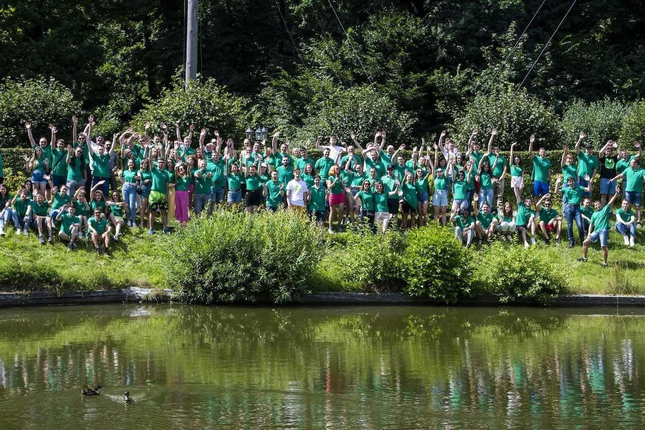 Agiliway employees in green shirts gathered outdoors beside a pond