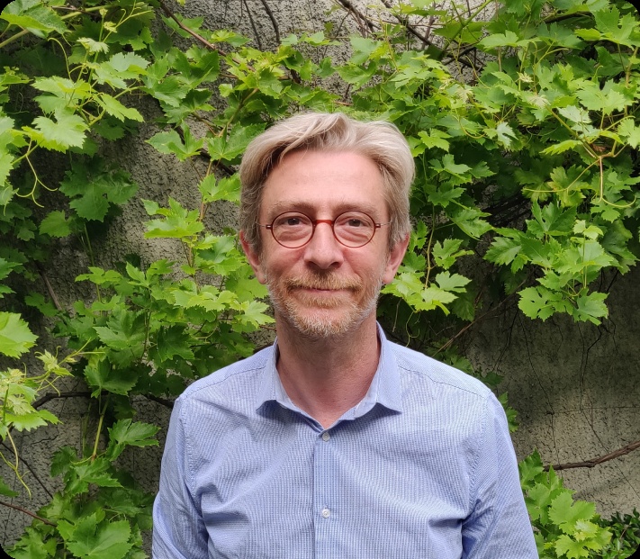 Agoranov director Jean-Michel Dalle wearing red glasses in front of green foliage