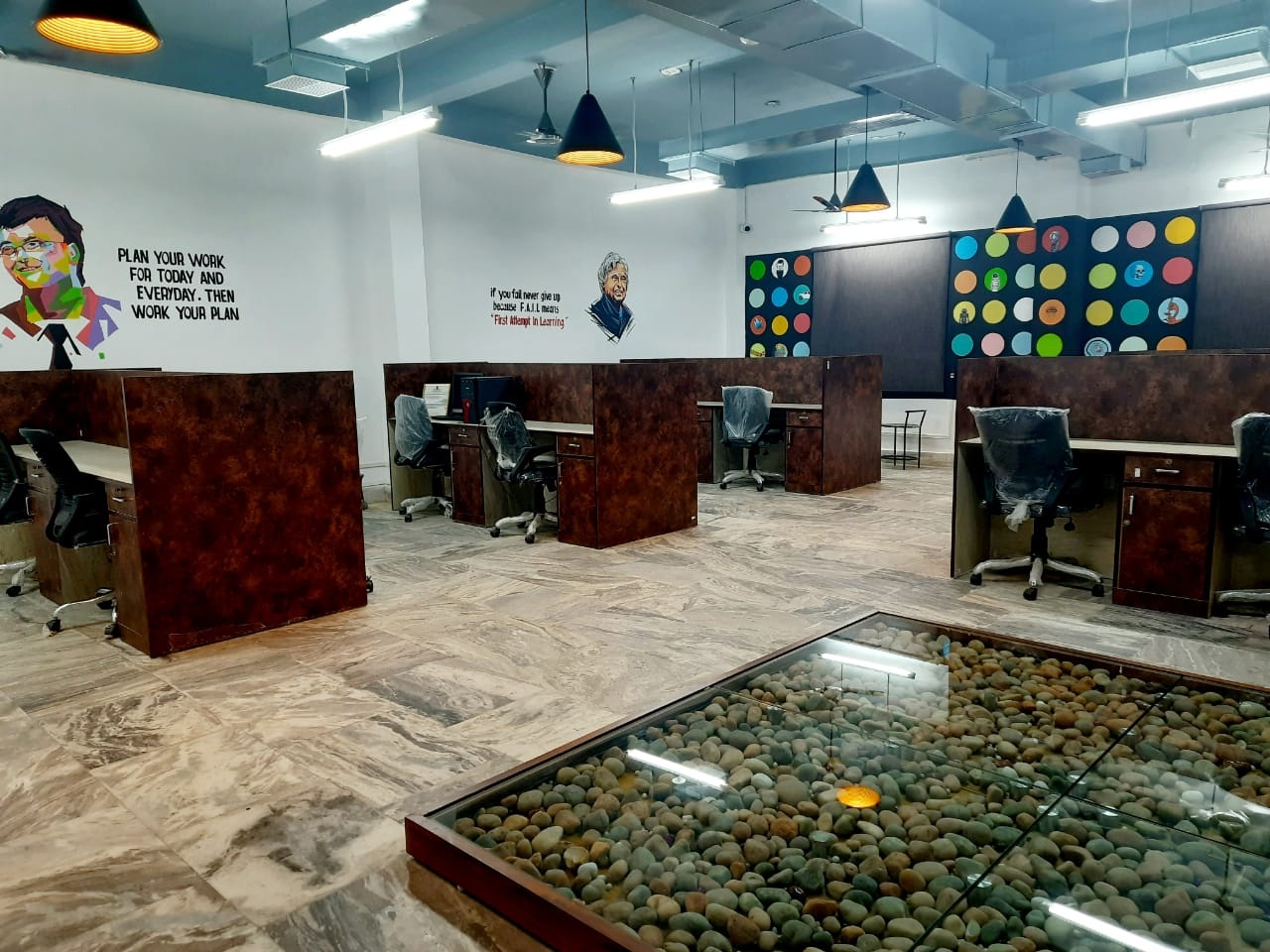Partitioned startup workspaces with wall portraits and pendant lights at AIC-Nalanda