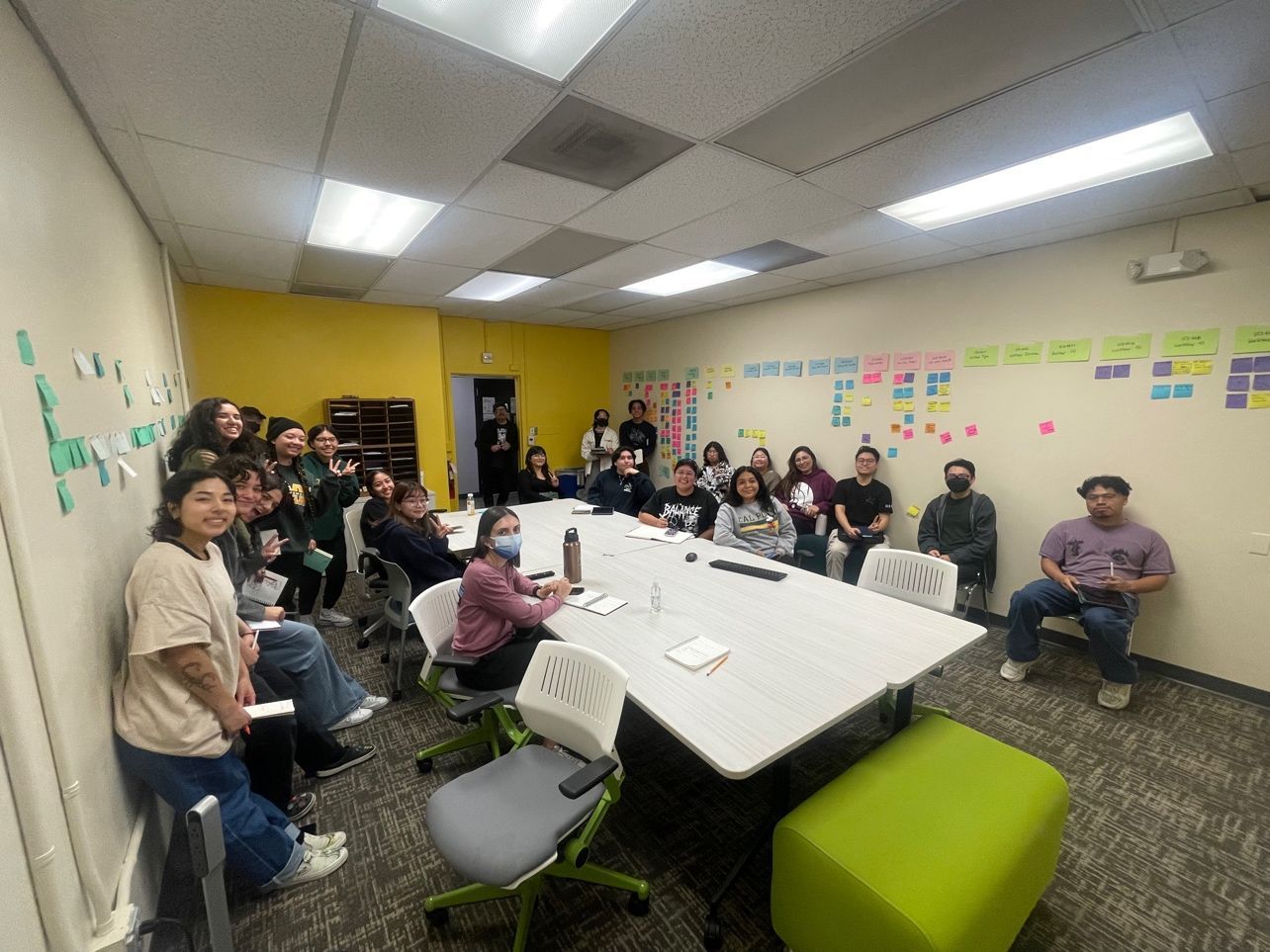 Cal Poly Pomona student designers gathered around tables, with colorful notes covering the classroom walls