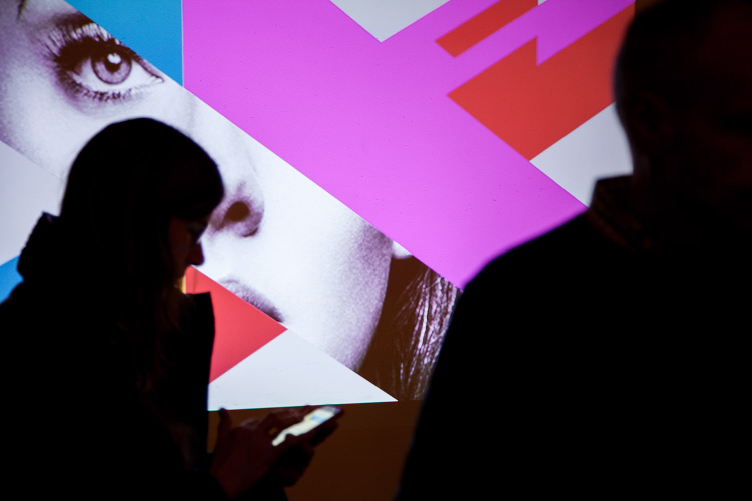Attendees silhouetted against a vivid pink and blue projected design at AIGA SF’s Landor studio tour