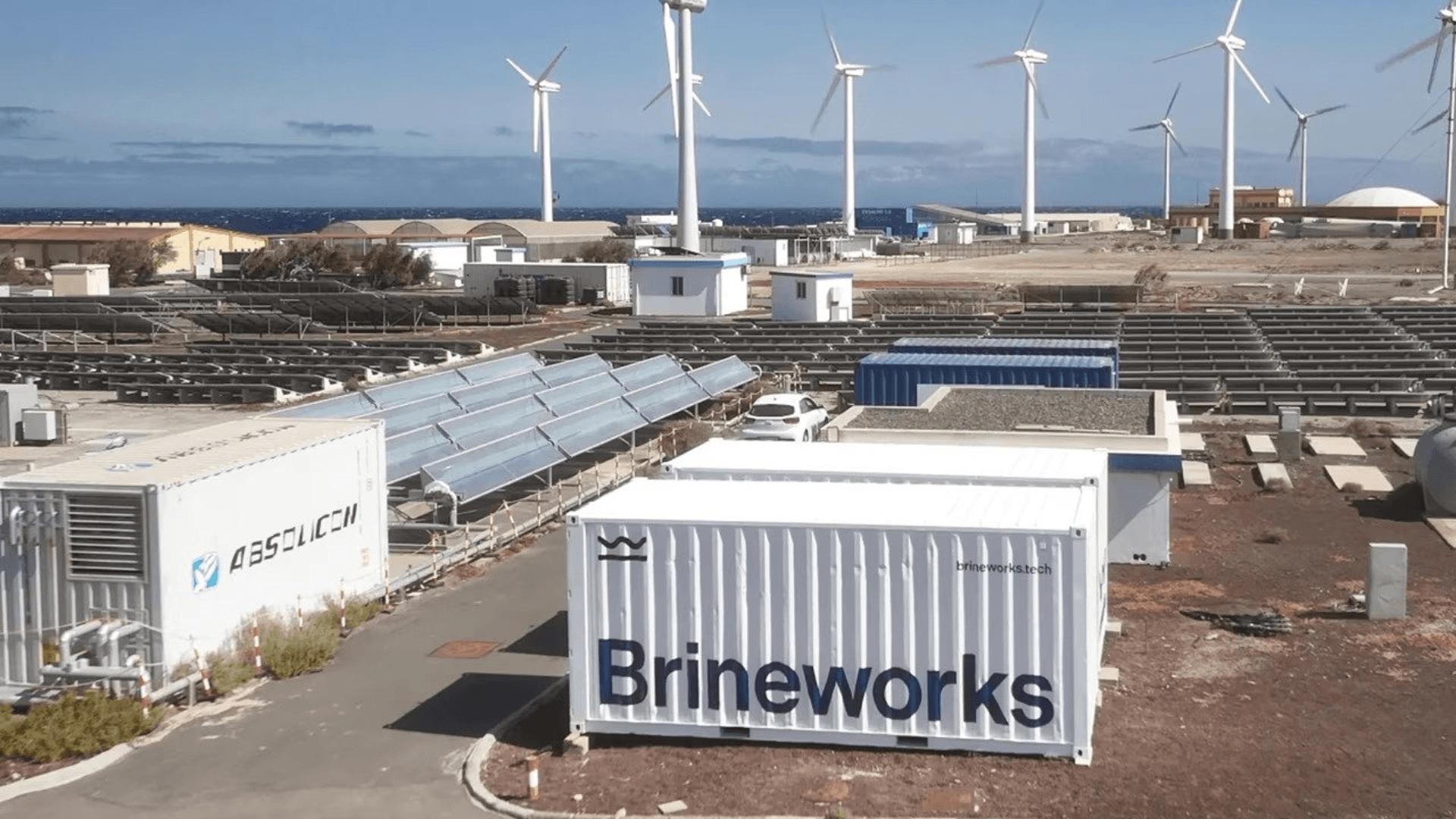 A Brineworks equipment container at a site with solar panels and wind turbines