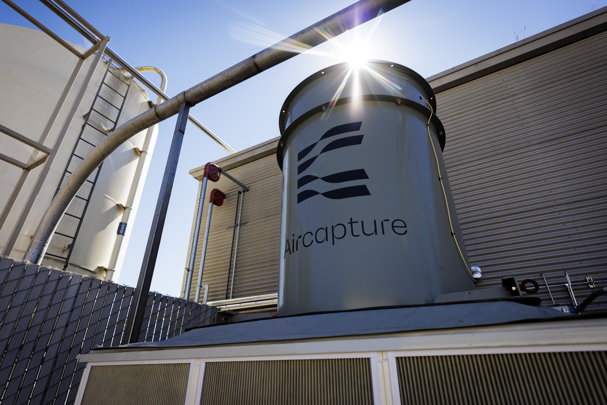 Aircapture’s cylindrical direct air capture equipment beside Almanac’s brewery under a bright sky