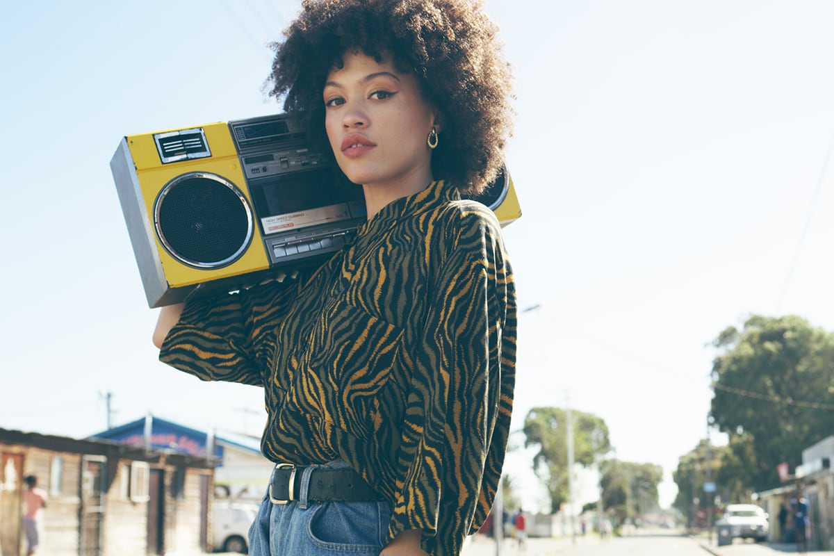 A woman carrying a yellow portable radio outdoors