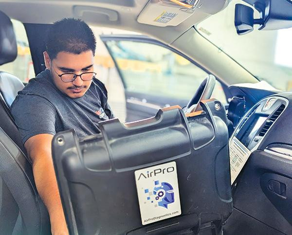 A technician using an AirPro diagnostic device inside a vehicle at ProColor Collision Etobicoke