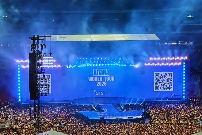 A blue-lit stadium stage announces Aitana's 2026 world tour before a large crowd