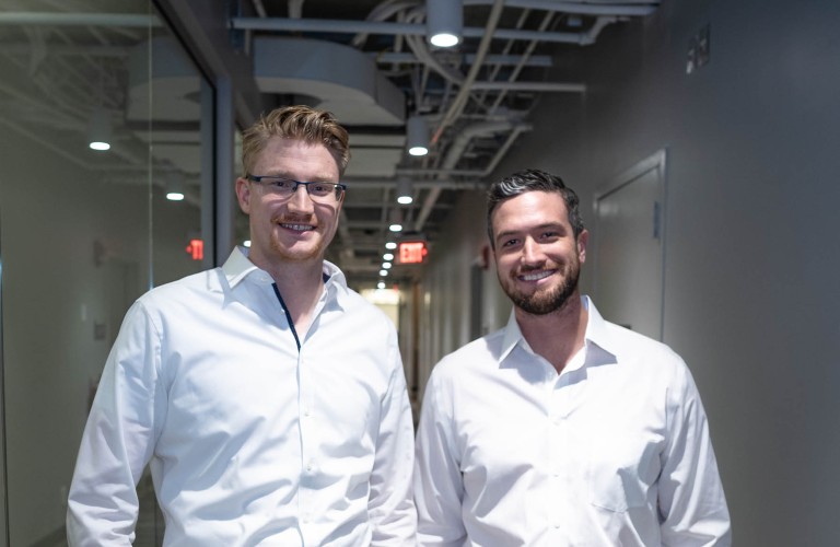 POM co-founders Lukas Lampe on the left and AJ Leahy on the right standing in an office corridor