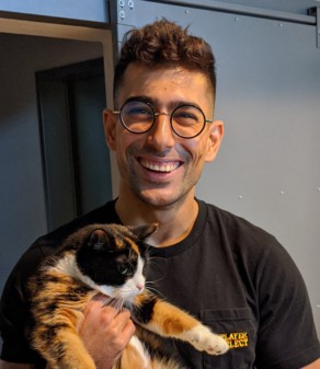 AJ Shewki smiling and holding the office cat
