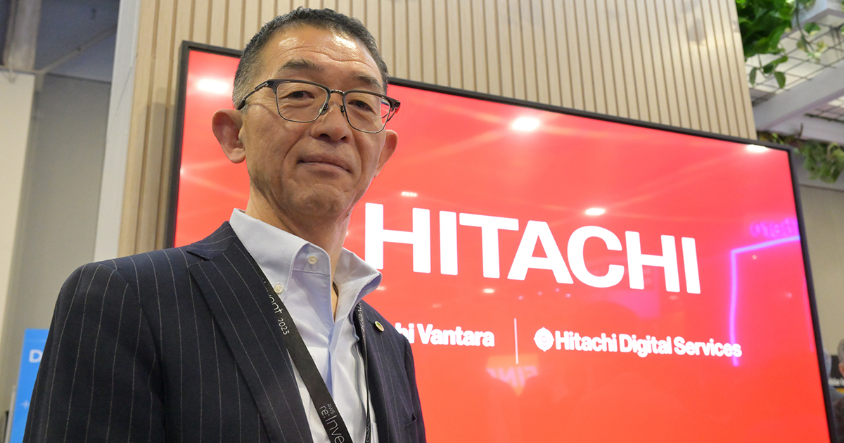 Akinobu Shimada standing at a Hitachi display during AWS re:Invent 2023