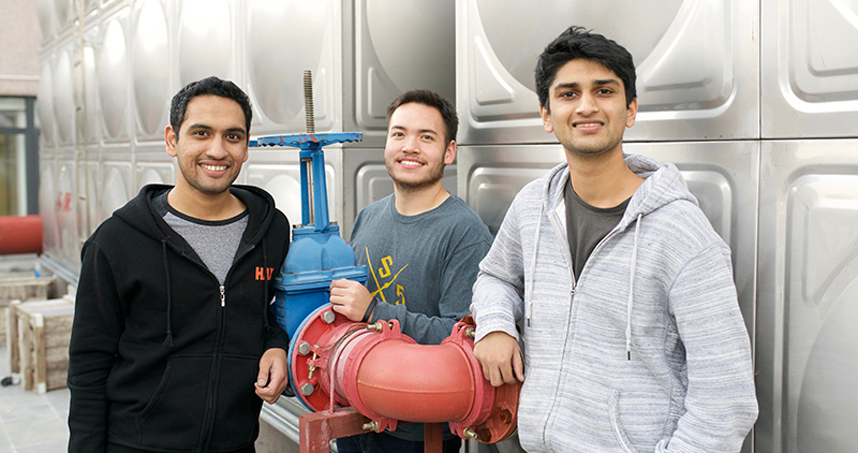 Amper co-founders Akshat Thirani, Philip House and Sachin Lal standing beside industrial equipment
