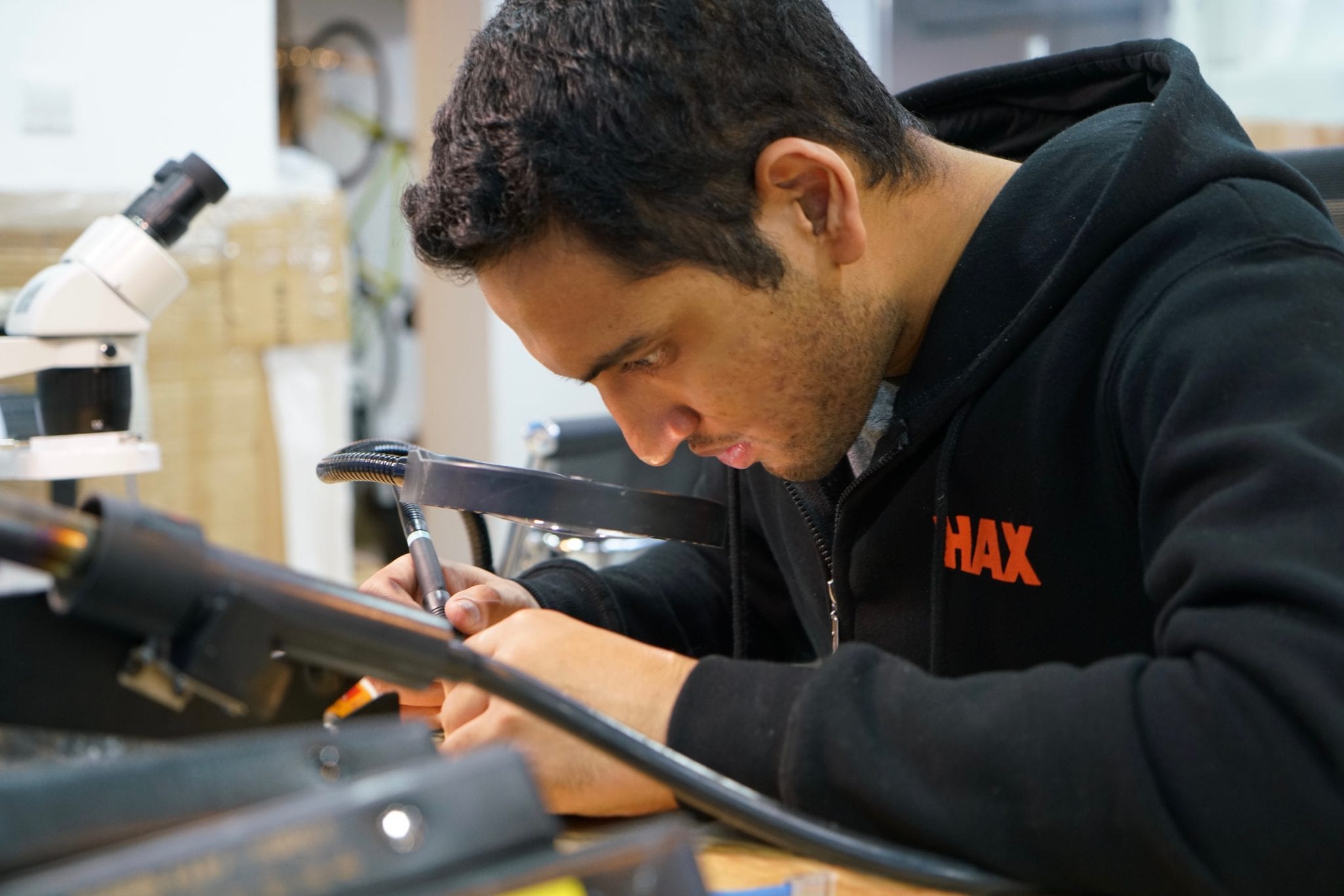 Akshat Thirani concentrating on electronics at a workbench while wearing a HAX sweatshirt