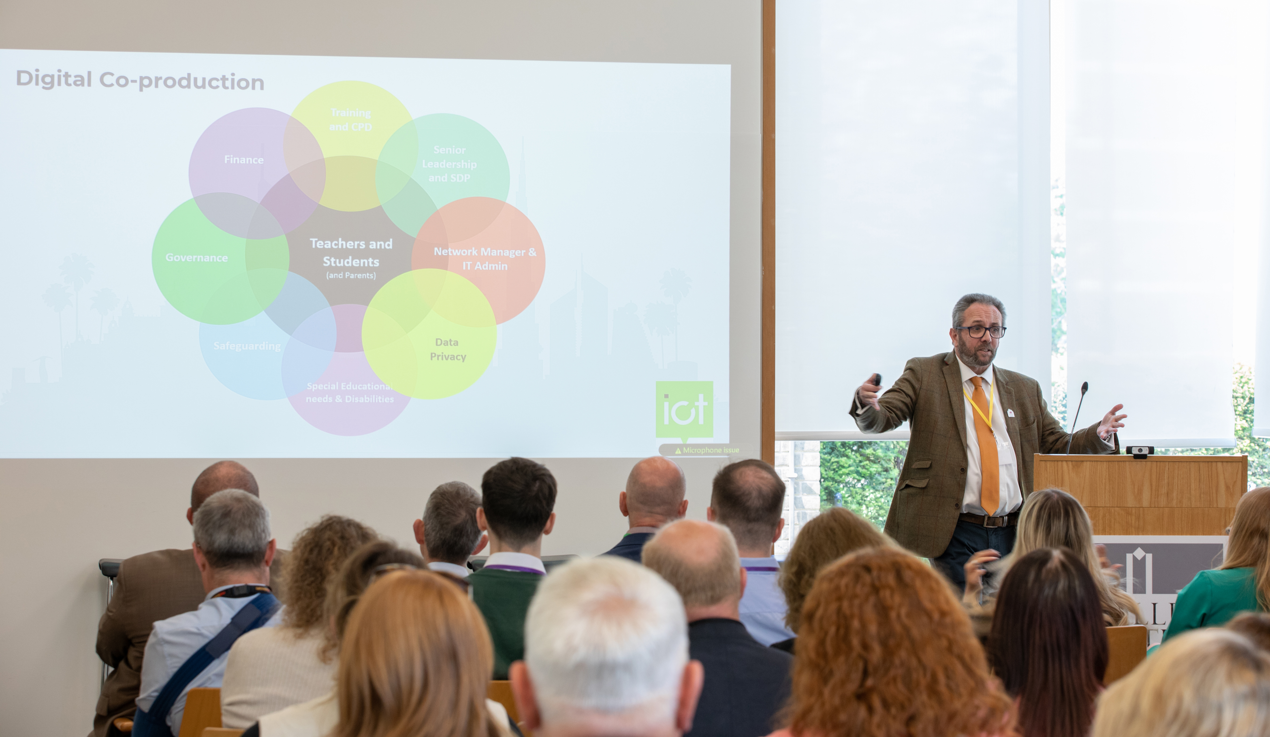 Al Kingsley speaking beside a projected diagram at the 2023 ICT Conference