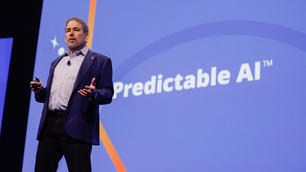Alan Trefler speaking onstage at PegaWorld 2026 beside the words Predictable AI