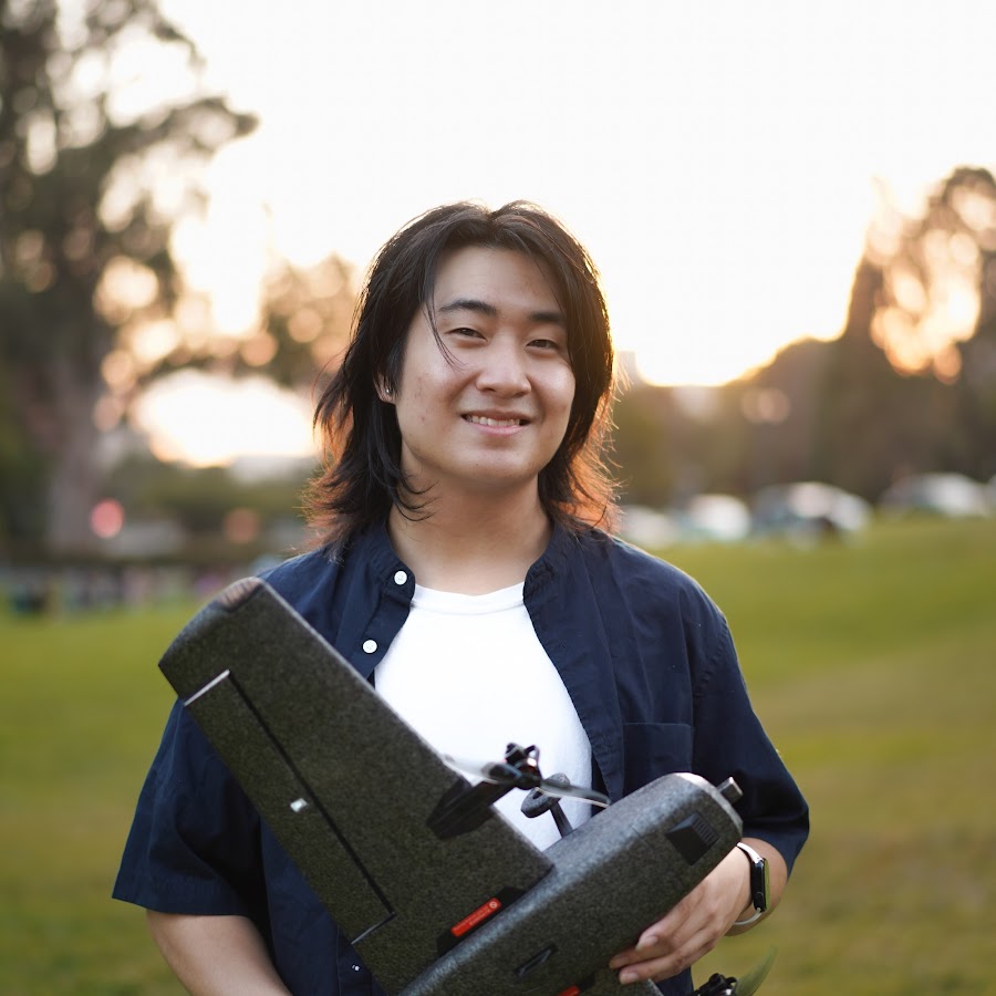 Alan Zhang holding a drone in a park at golden hour