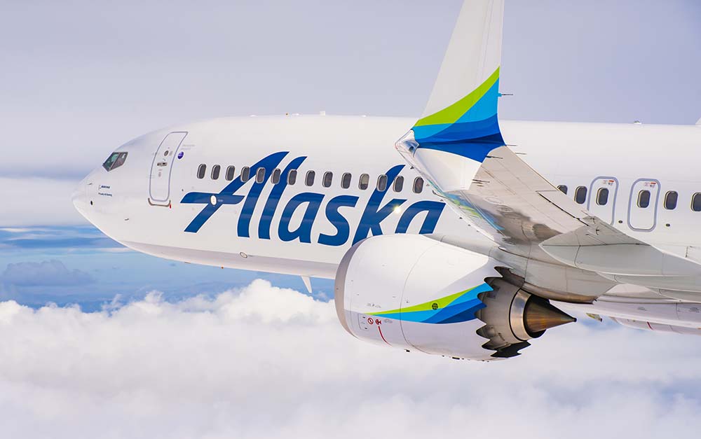 Alaska Airlines Boeing 737 flying over a mountainous landscape