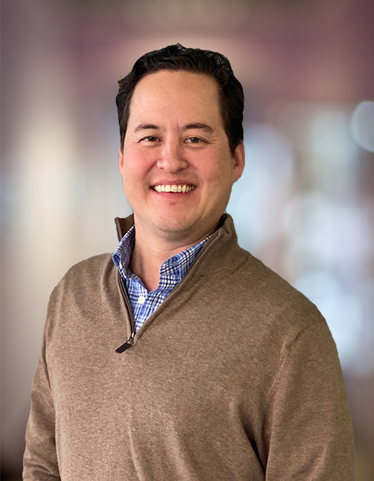 Albert Lilly smiling in a brown quarter-zip sweater