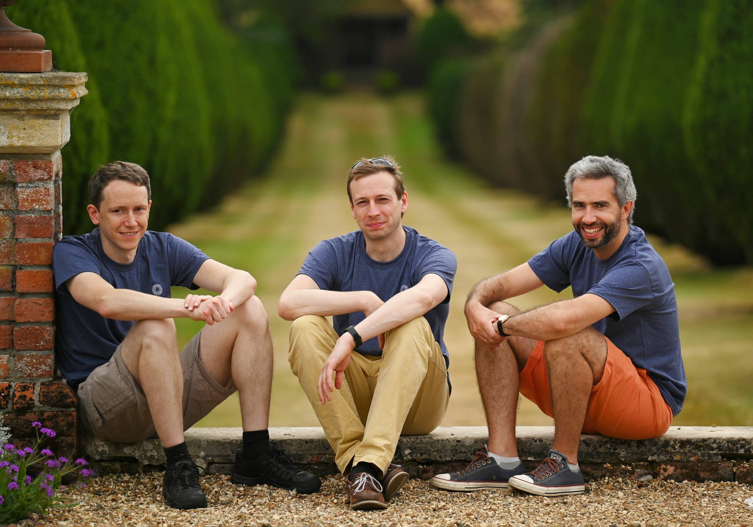 Three Phasecraft founders sitting together outdoors on a low garden wall