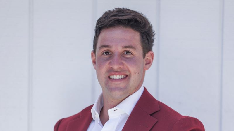 Alden Reiman wearing a red jacket against a pale background
