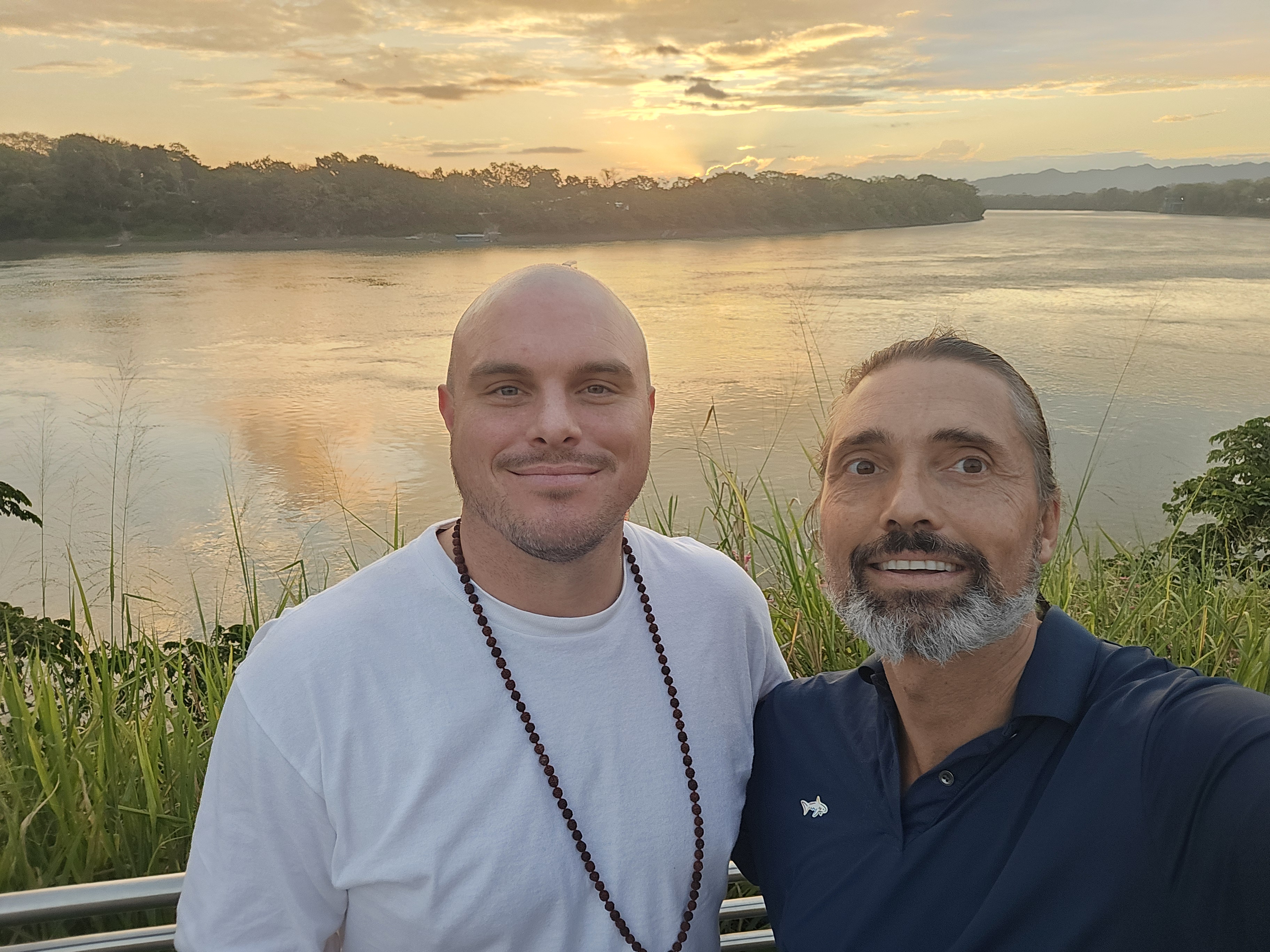 Two traveling companions beside a river at sunset, in a photograph published with Gicqueau’s March 2026 road-trip account