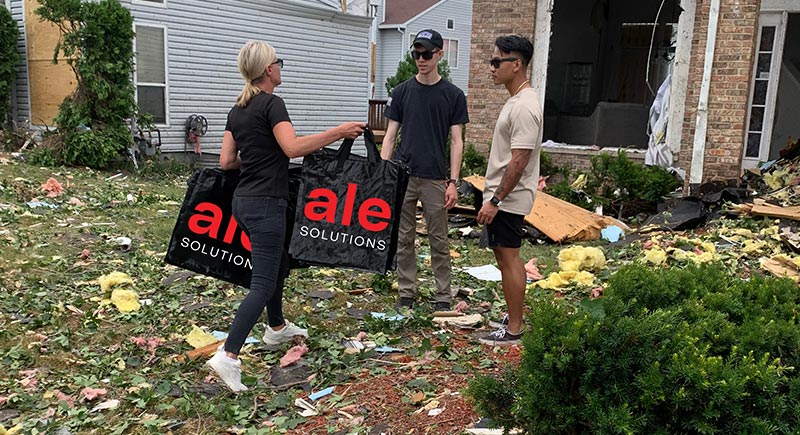 ALE catastrophe relief representatives with supply bags outside a damaged house