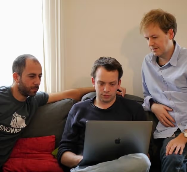Alex Dean, at left, and colleagues gathered around a laptop