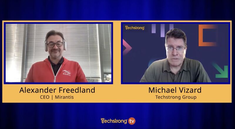 Alex Freedland in a red Mirantis jacket speaking with Techstrong host Michael Vizard in a remote interview