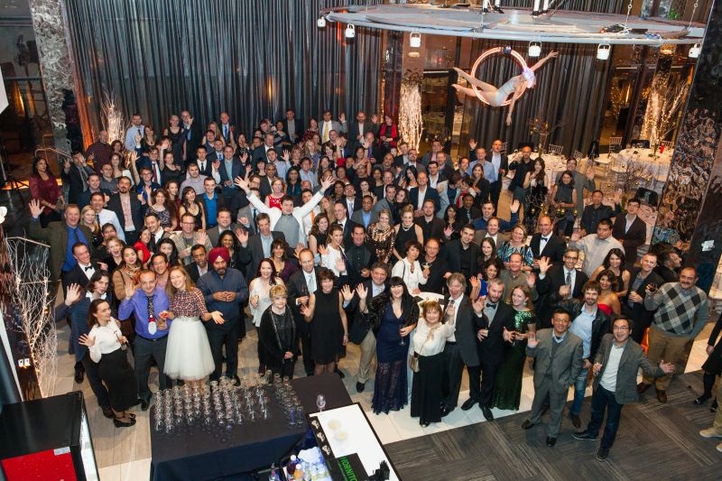 A large group gathered for a celebration in a warmly lit room, in a photograph shared by Alex Freedland