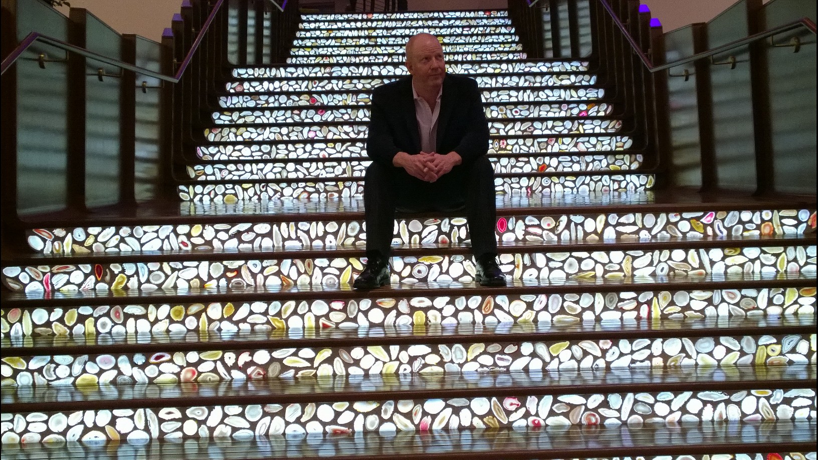 Alex Hinrichs seated midway up an illuminated staircase