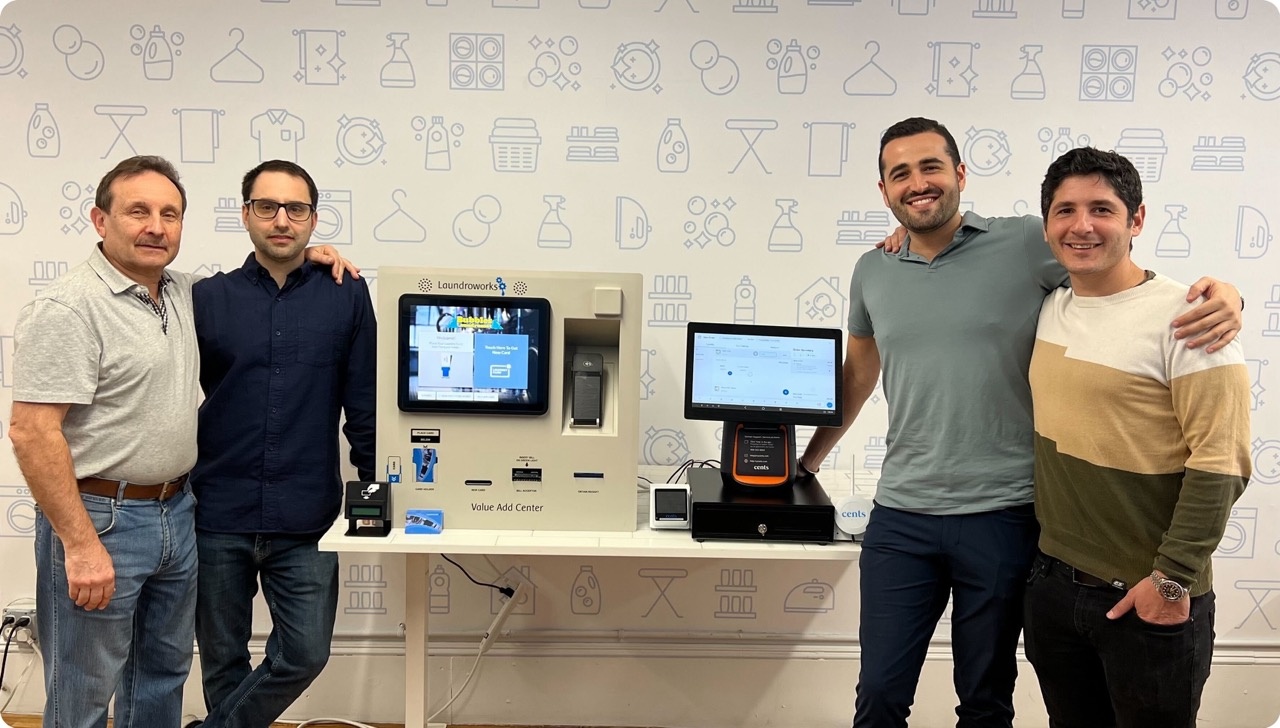 The Laundroworks and Cents teams standing beside laundry payment equipment