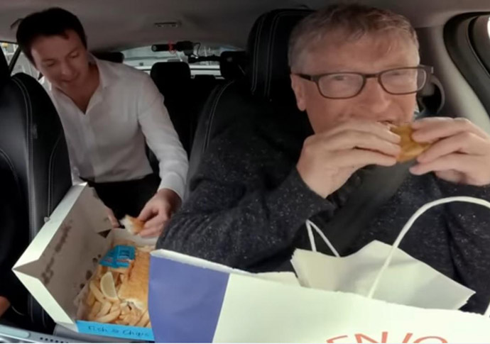Bill Gates eating takeaway in a Wayve vehicle, with Alex Kendall seated behind him