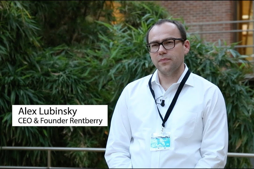 Alex Lubinsky wearing glasses and a white shirt, speaking on camera outdoors