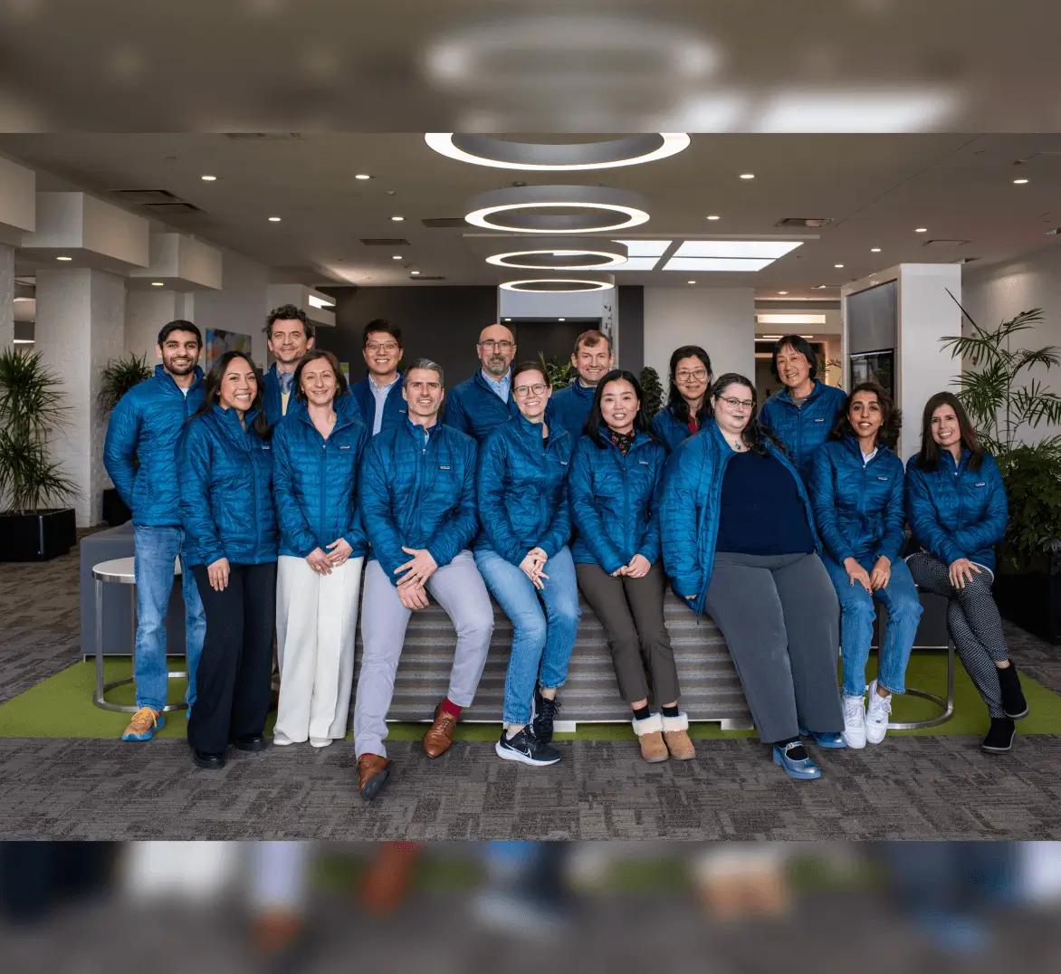 The Diagonal Therapeutics team gathered in the office wearing matching blue jackets.