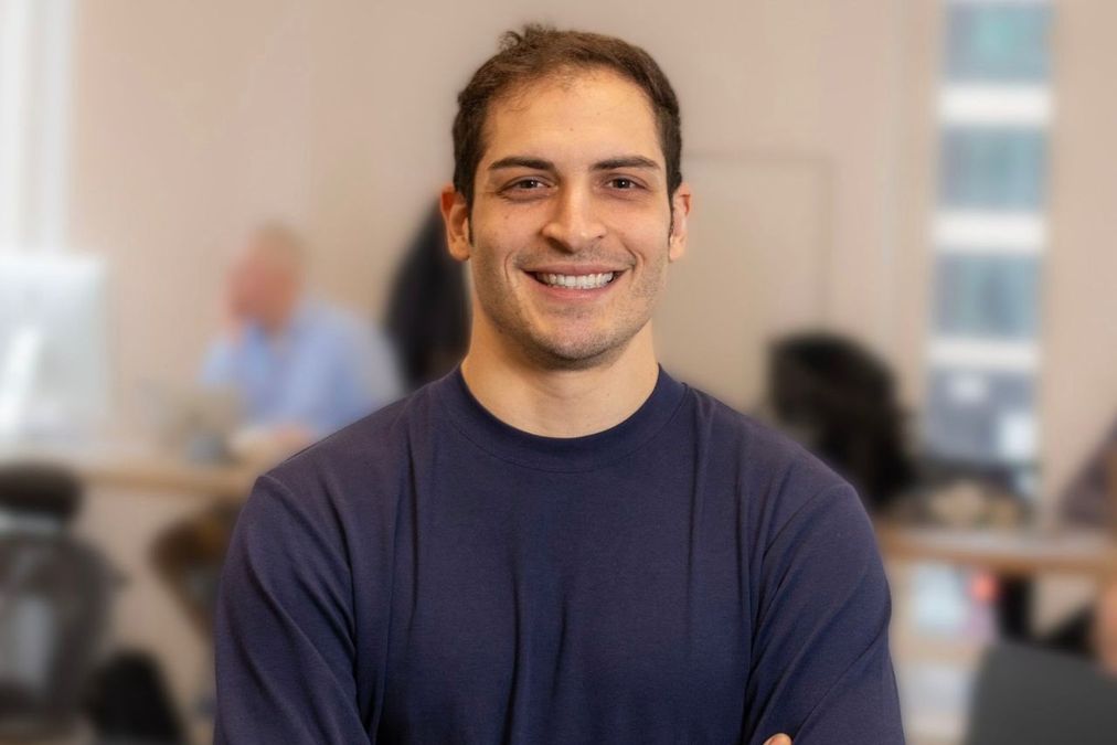 Alex Marantelos seated in an office, smiling at the camera