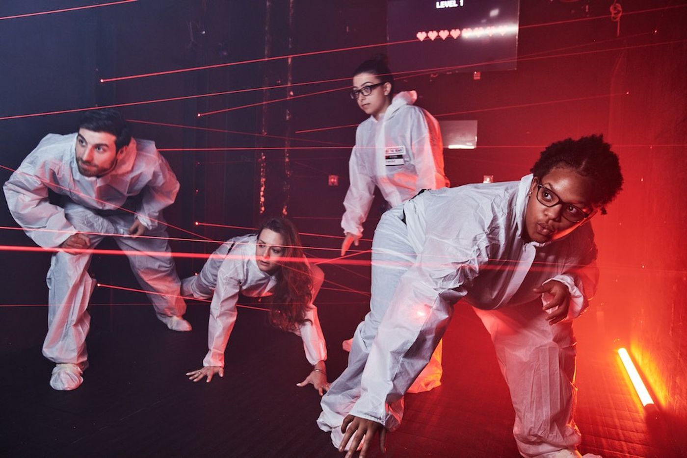 A group in protective suits navigates red laser beams at Beat The Bomb